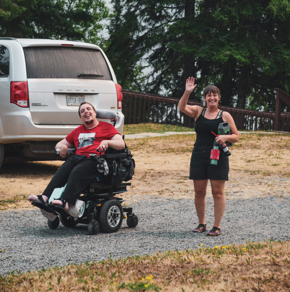 Female Waiving with Client in Wheelchair